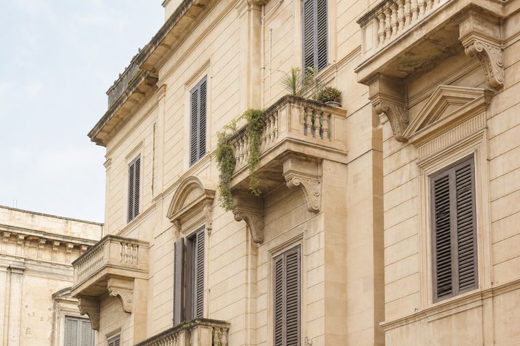 Angolo di un edificio residenziale europeo in muratura, con finestre allineate su più piani.