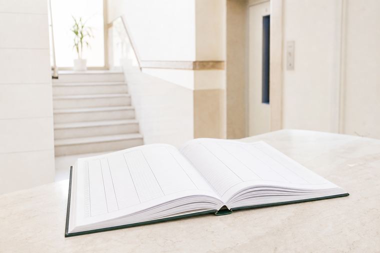 Una donna cammina lungo un edificio tenendo un libro aperto tra le mani.
